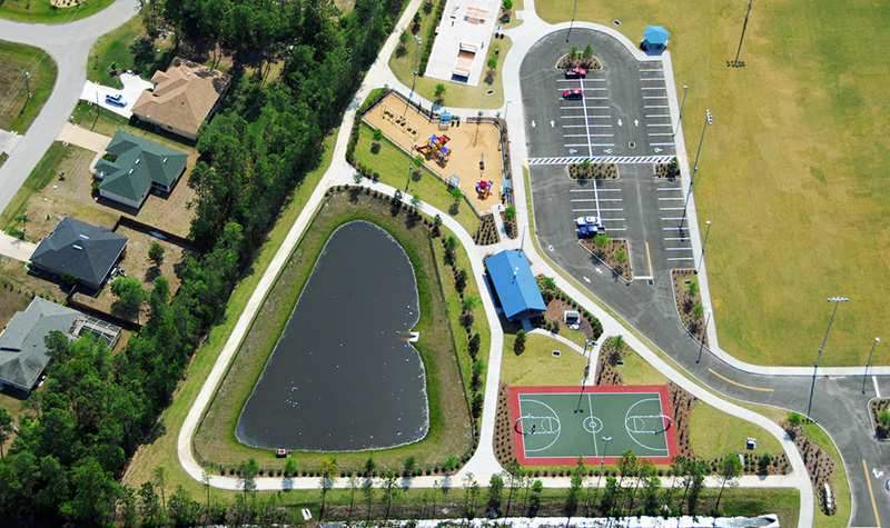 Aerial view of parking lot next to park and small pond