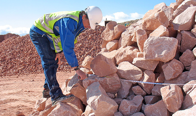 Person measuring pile of riprap rocks
