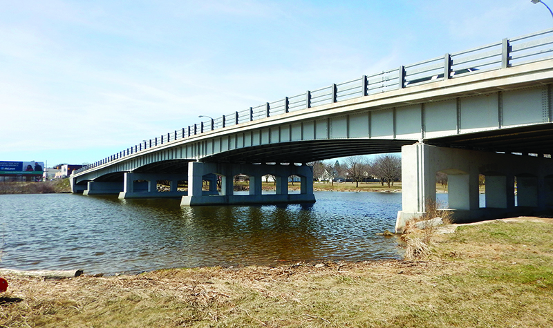 Bridge spanning river perspective from shore near water