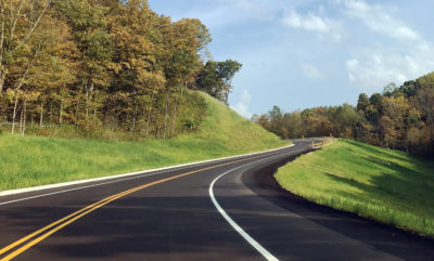 Road winding uphill through trees and grass