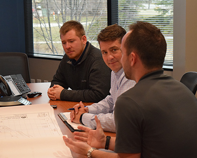 Three staff members having discussion at table.